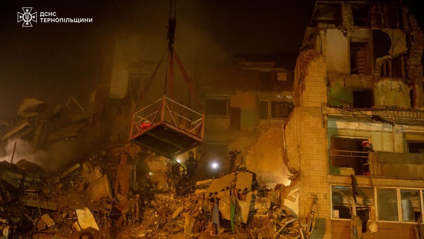 Рятувальники спускають тіло жінки, виявлене під завалами будинку, в який влучила російська ракета