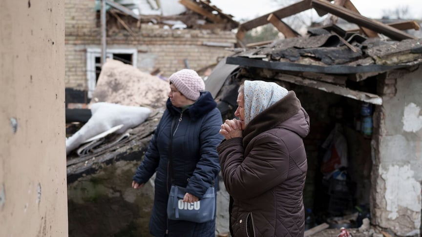 Жінка спостерігає, як працівники служби надзвичайних ситуацій прибирають уламки її будинку, зруйнованого після російського ракетного обстрілу в Києві, 29 грудня 2022 року