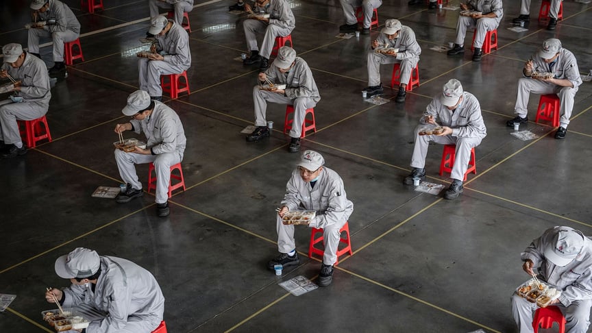 Workers eat sitting 1.5 meters away from each other at the Dongfeng Honda auto plant, in Wuhan, Wubei province, China. March 23, 2020.