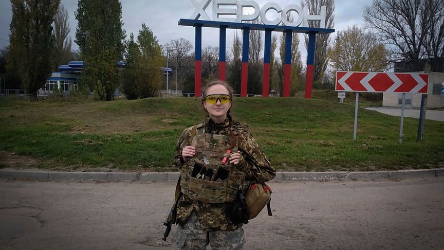 A Ukrainian servicewoman is photographed in front of the Kherson sign, November 11, 2022