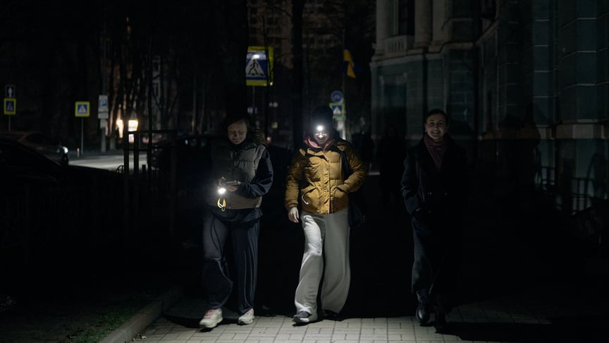 Люди в Києві ходять з увімкненими ліхтариками під час відключень електроенергії, 7 грудня 2025 року