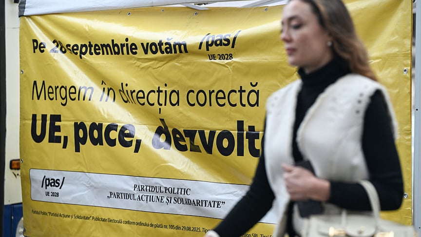 Ілюстративне фото. Жінка проходить повз агітаційний плакат партії «Дія та Солідарність» у день парламентських виборів у Молдові