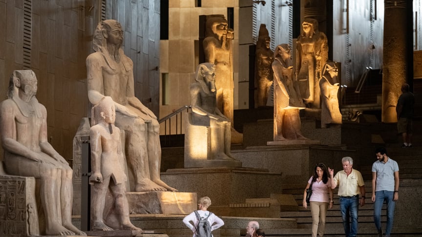 Відвідувачі проходять біля стародавніх єгипетських статуй, що розташовані вздовж Великих сходів у Великому єгипетському музеї