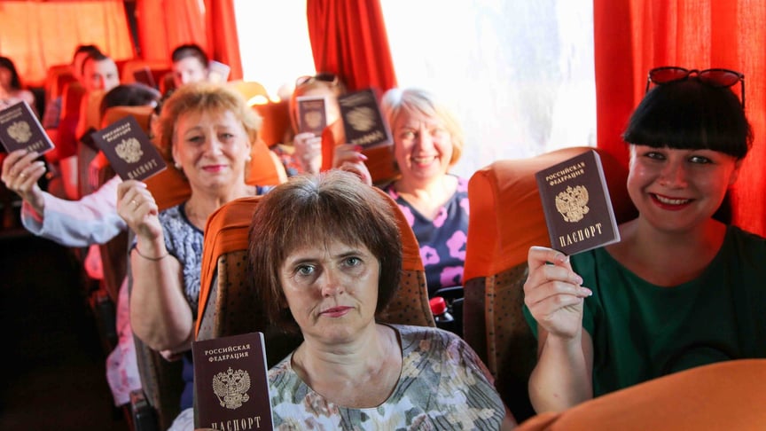 Люди показують свої російські паспорти в автобусі, що прямує в Росію, на автобусній зупинці в Донецьку на сході України 27 червня 2020 року