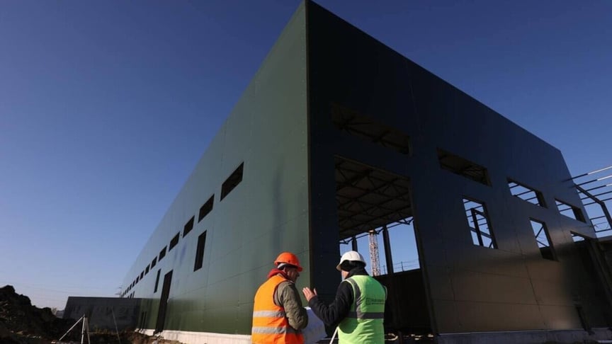 Двоє працівників стоять поруч з будмайданчиком, де зводять сміттєпереробний завод, Львів