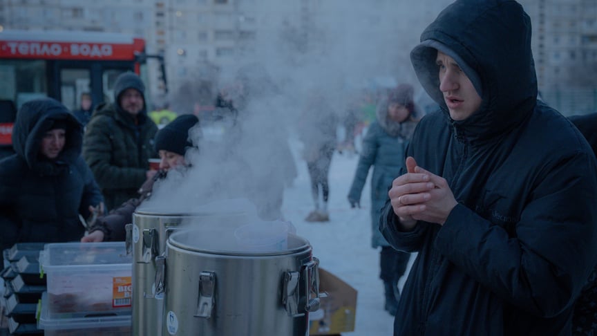 Люди отримують їжу та гарячі напої у дворі багатоквартирного будинку, пошкодженого російським безпілотником 3 лютого 2026 року в Харкові