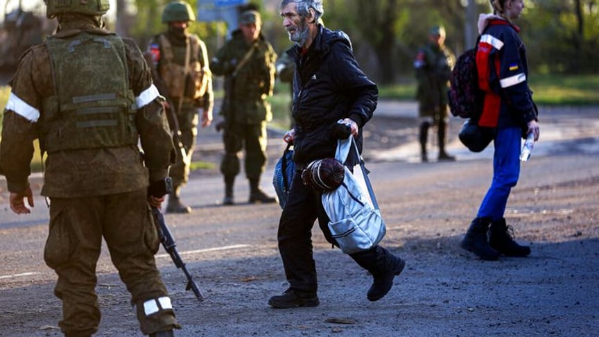 A civilian who escaped from Azovstal walks to a bus past the Russian military on May 6, 2022