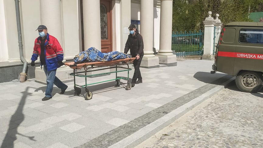 Работники везут тело умершего в здание морга