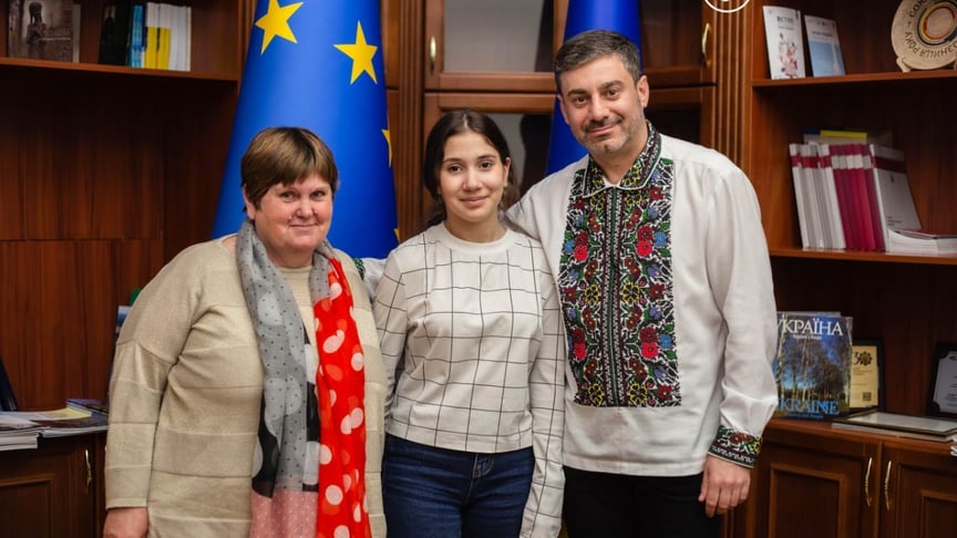 Дитина, яку повернули з росії, стоїть між бабусею та омбудсменом