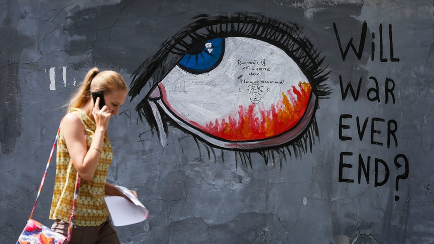 A woman walks past a graffiti in Kyiv, Ukraine on June 30, 2015.