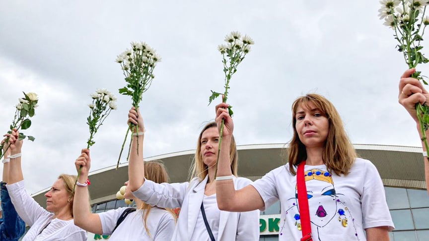 Женщины держат в руках полевые цветы, стоя у Комаровского рынка в Минске, в знак протеста против насилия на митингах, 12 июня 2020 года