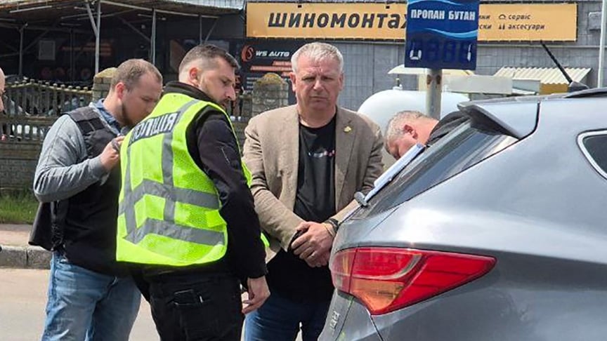 Чоловік, схожий на міського голову Бердичева Сергія Орлюка, стоїть в оточенні правоохоронці на вулиці міста
