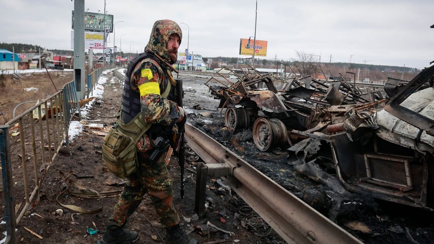 Озброєний український чоловік стоїть біля залишків російської техніки, Буча під Києвом, 1 березня 2022 року