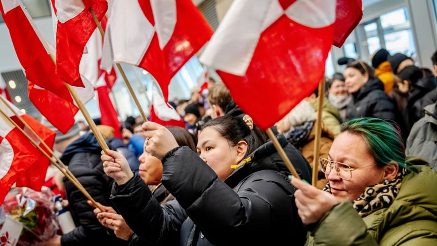 Люди тримають гренландські прапори, вітаючи міністерку закордонних справ Гренландії після її приземлення в аеропорту столиці Гренландії Нуука 20 січня 2026 року