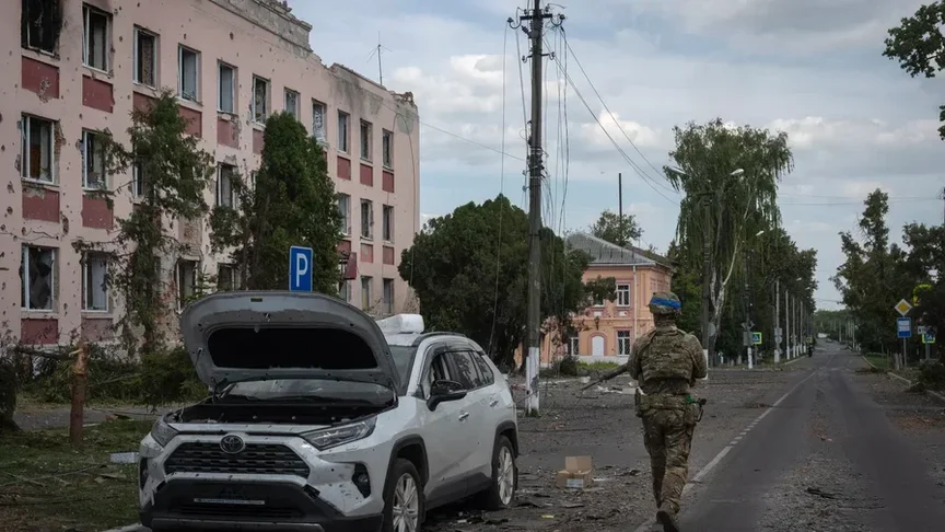 Український військовий проходить повз пошкоджені автівку та будівлю в Суджі, Курська область, 16 серпня 2024 року