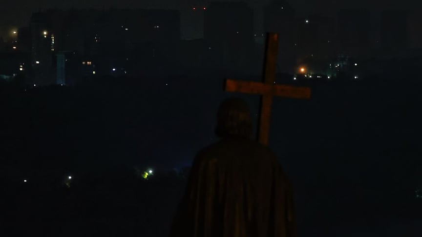 Пам'ятник князю Володимиру на Володимирській горі на тлі житлових районів, які залишаються без електроенергії через російські удари 10 жовтня 2025 року в Києві.