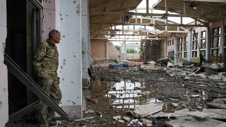 Украинский военнослужащий смотрит на руины спортивного комплекса Национального технического университета в Харькове, поврежденного при обстреле, 24 июня 2022 года