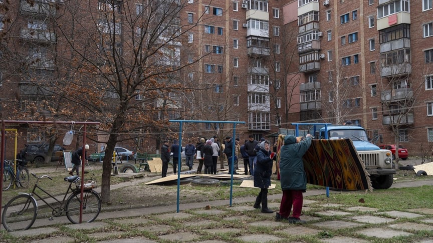 Мешканці будинку у Слов’янську розбирають фанерні панелі, щоб закрити пошкоджені війна, 7 грудня 2025 року