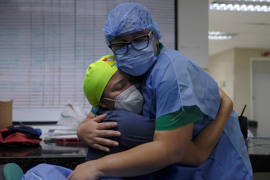Медицинские работники обнимаются после смены в государственной больнице Ана Франциска Перес де Леон II в Каракасе, Венесуэла, 23 марта 2021 года